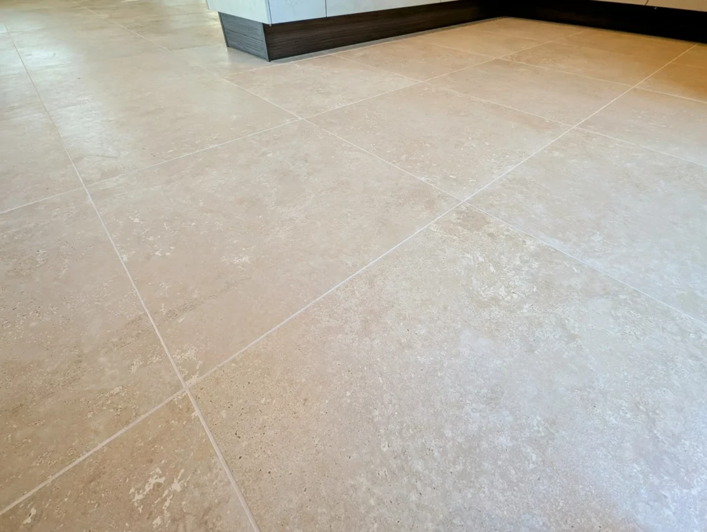 Rénovation intérieure d'une cuisine avec un carrelage grand format ton pierre. Projet de rénovation par éco rénovation groupe
