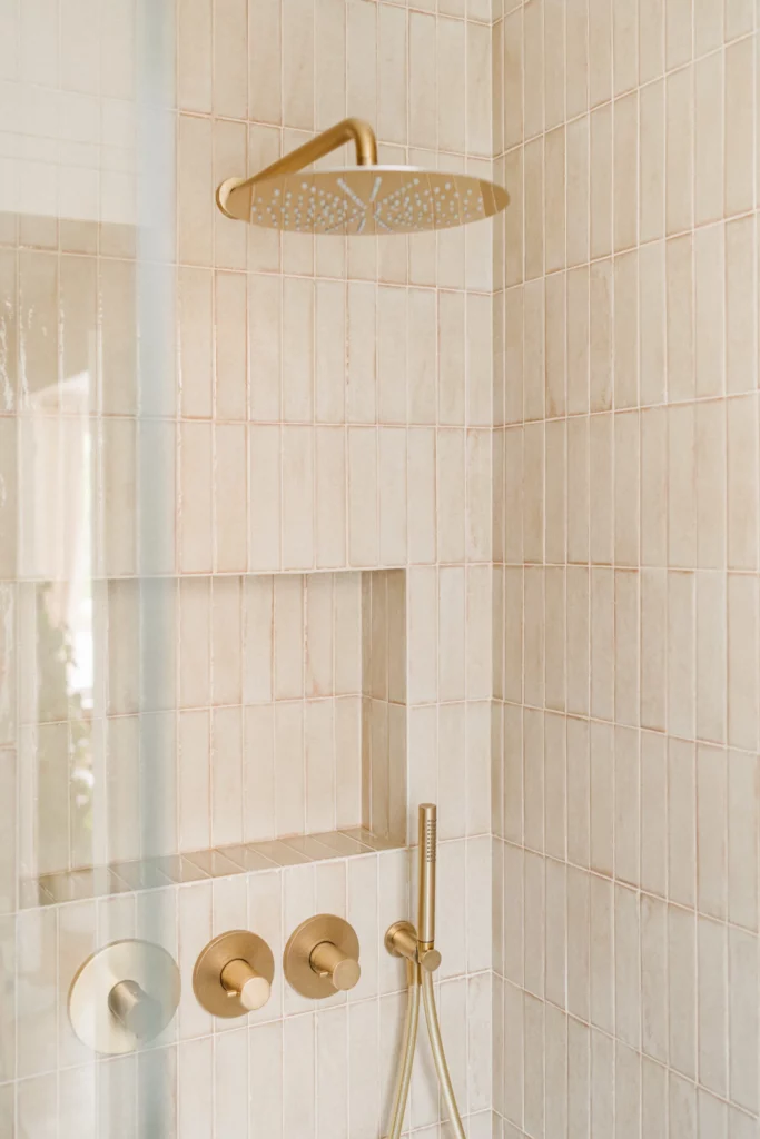 Douche rénovée avec faïence rose en petits carreaux rectangulaires et robinetterie en laiton pour un style élégant et chaleureux dans un appartements à Nantes