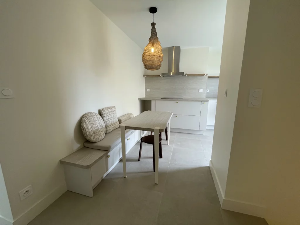 Cuisine équipée blanc et gris avec table, plan de travail et banquette – rénovation près de Rennes