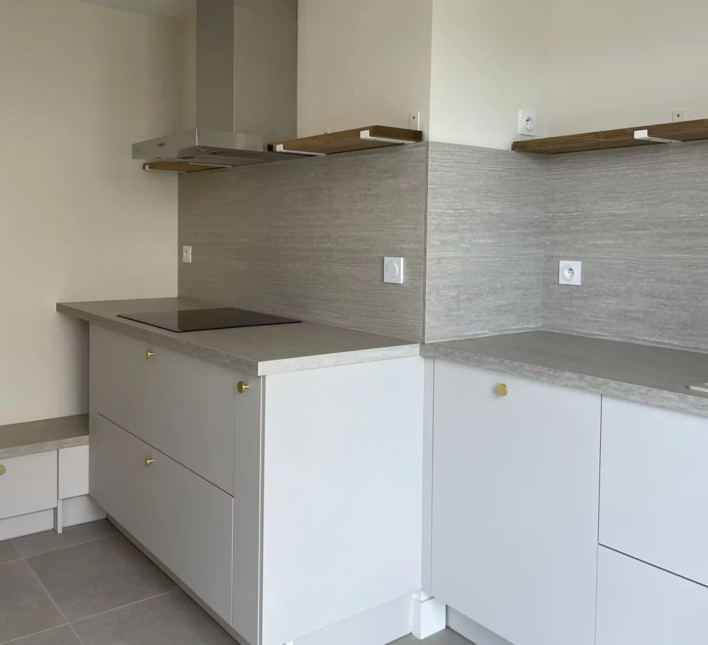Vue détaillée de la cuisine rénovée gris clair et doré dans une maison à Orgères (35)