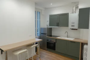 Cuisine vert sauge entièrement équipée dans un appartement T2 rénové à Rennes.