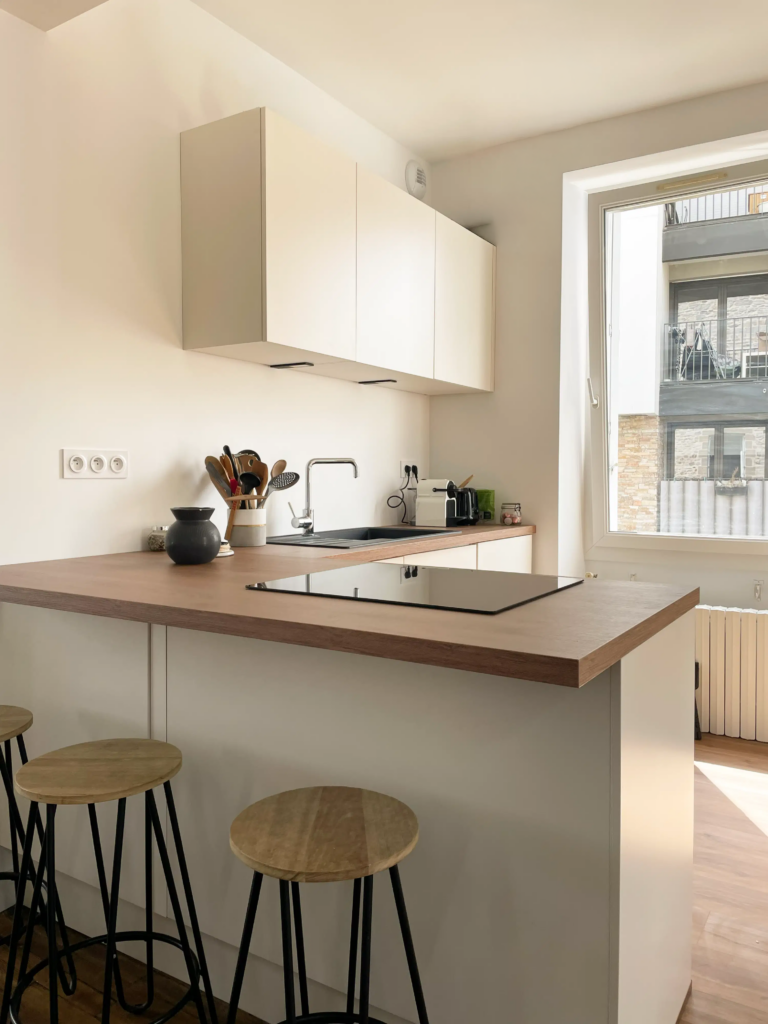 Cuisine rénovée beige et bois avec murs blancs repeints et nouveau sol, réalisée lors d’un projet de rénovation intérieure