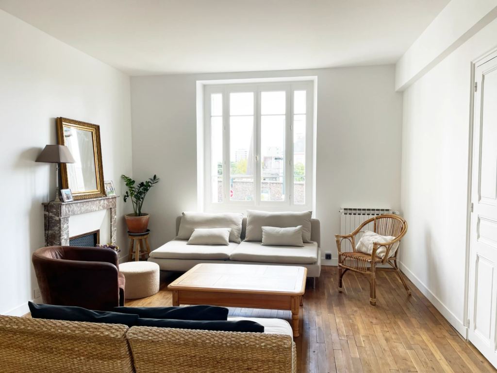 Salon rénové avec canapé, cheminée ancienne restaurée et porte intérieure refaite lors d’un projet de rénovation de maison